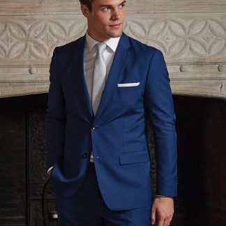 a handsome man stands in a suit in front of a fire place.