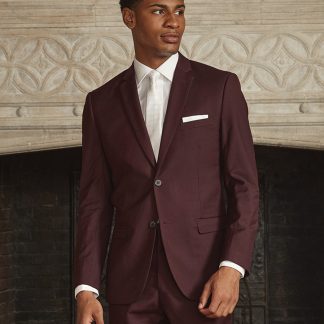 A handsome man stands in a suit in front of a fire place.