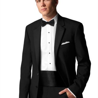 A Man in a black tuxedo stands with one hand in his pocket