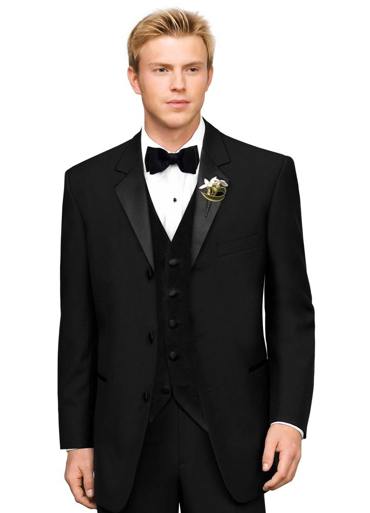 A Man in a black Tuxedo stands with his arms at his side
