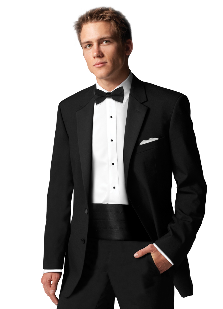 A Man in a black tuxedo stands with one hand in his pocket